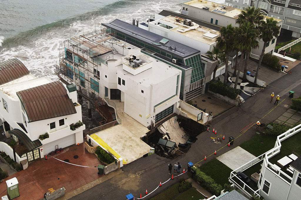 This aerial view shows a sinkhole on a street and driveway of a seaside home affected by large swells produced by Hurricane Marie in Malibu, California, on September 8, 2026. Hurricane Marie stayed well offshore of Southern California during Labor Day weekend but its large swells produced dangerous surf and rip currents, with waves reaching around 10 feet in some areas.