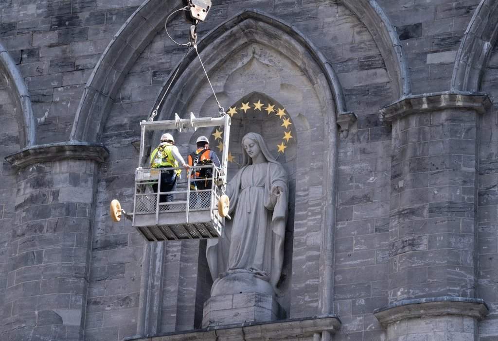 Workers inspect a statue on the facade of the Notre-Dame Basilica in Montreal on Thursday, August, 29, 2019. THE CANADIAN PRESS/Paul Chiasson.