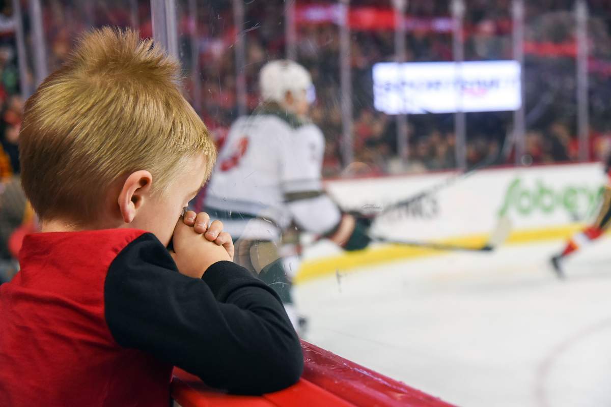A tired young fan rubs his eyes during the first period of an NHL game where the Calgary Flames hosted the Minnesota Wild on December 6, 2018, at the Scotiabank Saddledome.