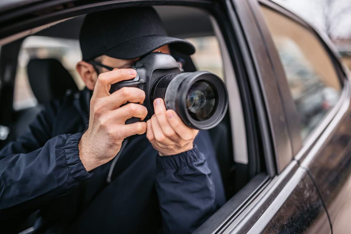 A photographer takes pictures from inside a car.
