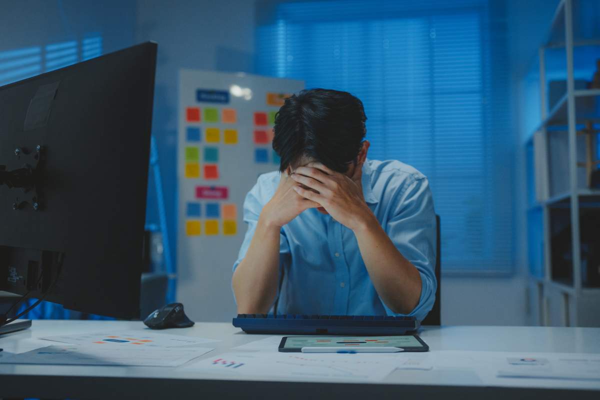 Tired businessman experiencing workplace stress and burnout while reviewing documents late at night.