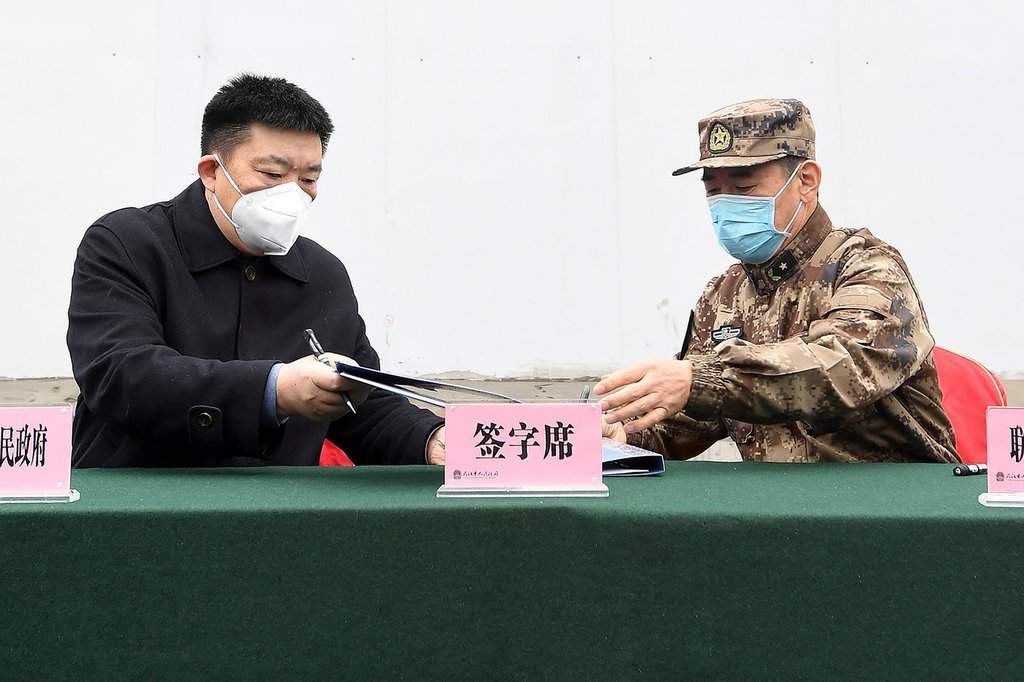 Zhou Xianwang, left, the mayor of Wuhan, exchanges documents with Bai Zhongbin, right, deputy commander-in-chief of China's People's Liberation Army (PLA) Joint Logistic Support Force, during a handover ceremony at the Huoshenshan temporary field hospital in Wuhan in central China's Hubei Province, Feb. 2, 2020. (Chinatopix via AP).