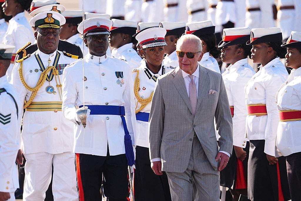 Britain's King Charles III walks by the guard of honour, made up of members of the Royal Bahamas Police Force and the Royal Bahamas Defence Force, as he arrives at Lynden Pindling International Airport, in Nassau, at the start of the royal visit to The Bahamas on October 27, 2026.  