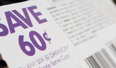 Close-up of a coupon touting extreme frugality: SAVE 60¢ on six Dannon single-serve cups, barcode in view.