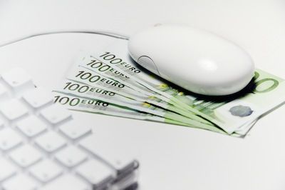 A computer mouse on 100 euro bills next to a keyboard highlights a disadvantage of online banking.