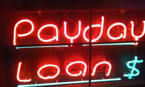 Neon sign in red and blue reads Payday Loan with a dollar sign, highlighting why payday loans are bad for your finances.
